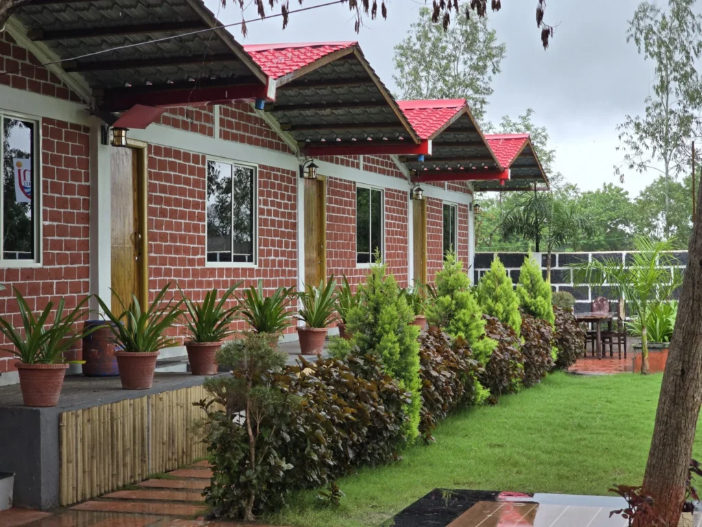 Brick cottages, planted walkway and lawn at Kunj Resort