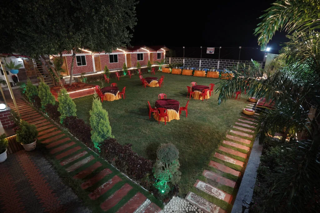 Party lawn with tables and chairs photographed at night at Kunj Resort