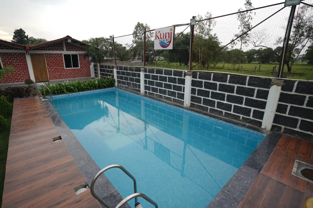 Swimming pool beside brick buildings at Kunj Resort